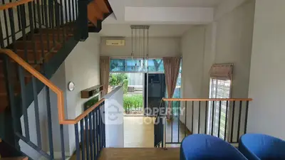 Spacious modern living room with staircase and large windows offering garden view.