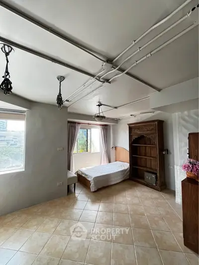 Spacious bedroom with large windows and elegant wooden furniture, offering a serene and bright living space.