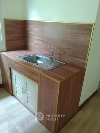 Compact kitchen with wooden cabinetry and stainless steel sink