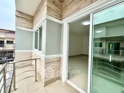 Modern balcony with sleek railing and sliding glass doors in a contemporary apartment.