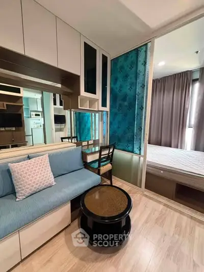 Modern apartment interior with cozy living area and stylish bedroom separated by sliding glass doors.