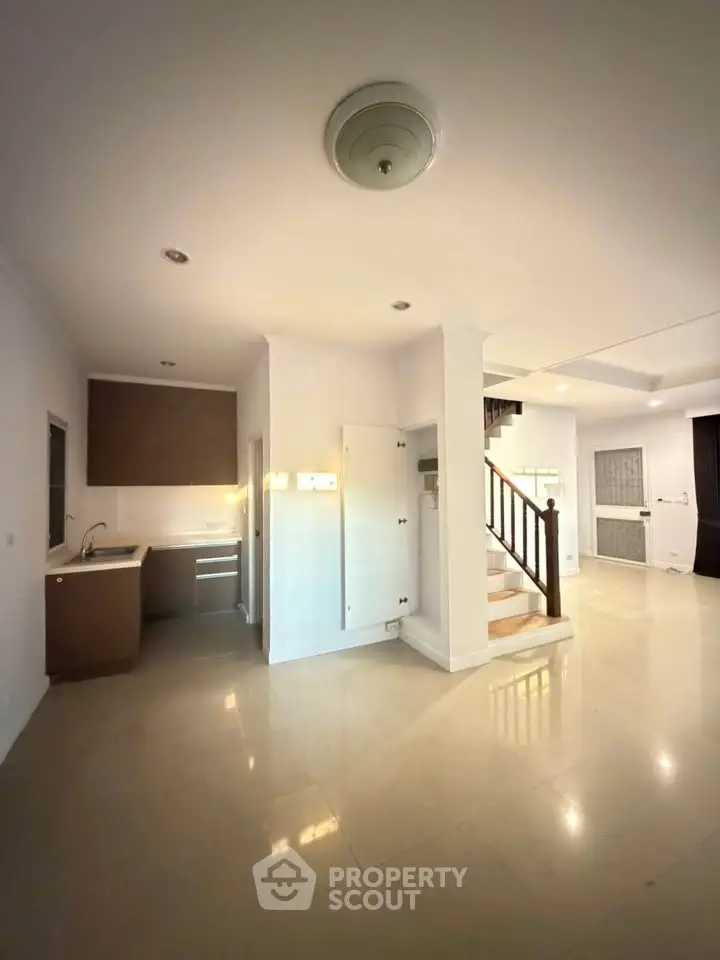 Spacious open-plan living area with modern kitchen and elegant staircase