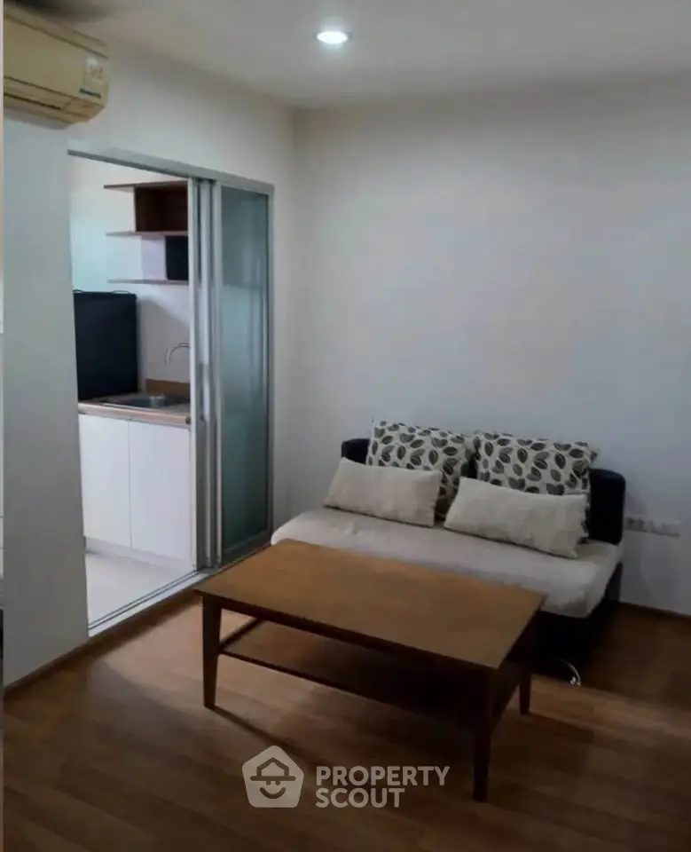 Cozy living room with wooden flooring and compact kitchen in modern apartment.