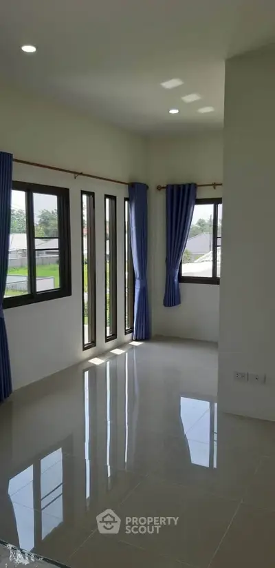 Bright and airy corner unit with large windows and blue curtains, offering a serene view.