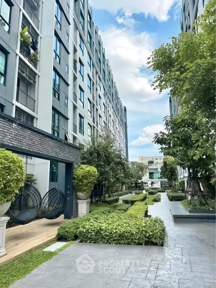 Modern apartment building with lush garden and stylish outdoor seating area.