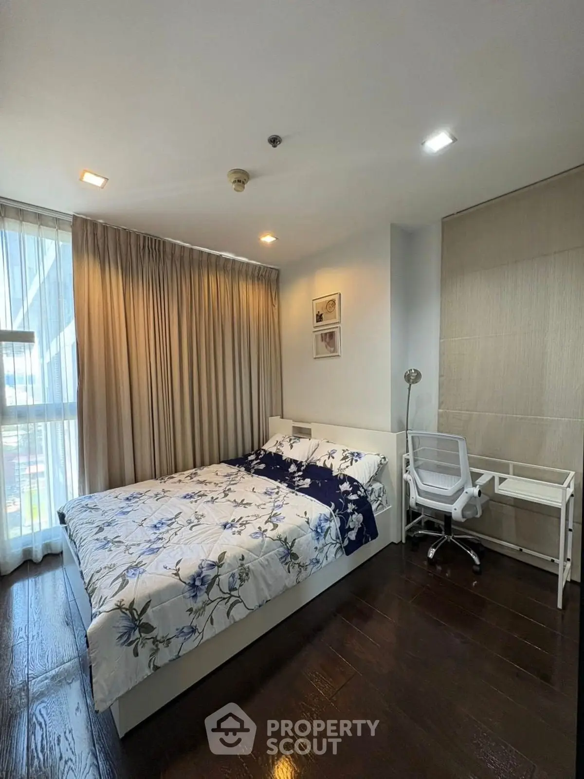 Cozy bedroom with modern decor and natural light, featuring a study desk and elegant curtains.