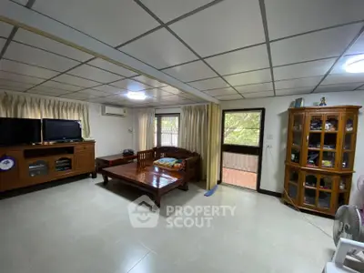 Spacious living room with wooden furniture and large windows for natural light.