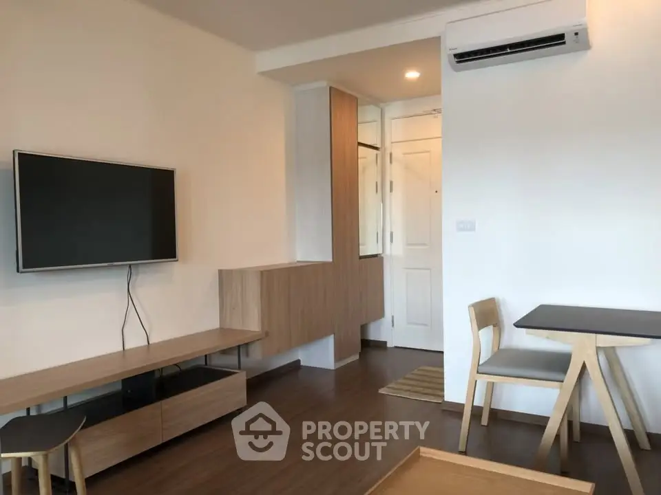 Modern living room with sleek furniture and wall-mounted TV in a cozy apartment.