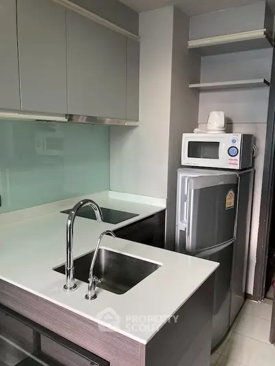 Modern kitchen with sleek cabinetry, double sink, and compact appliances in a stylish apartment.