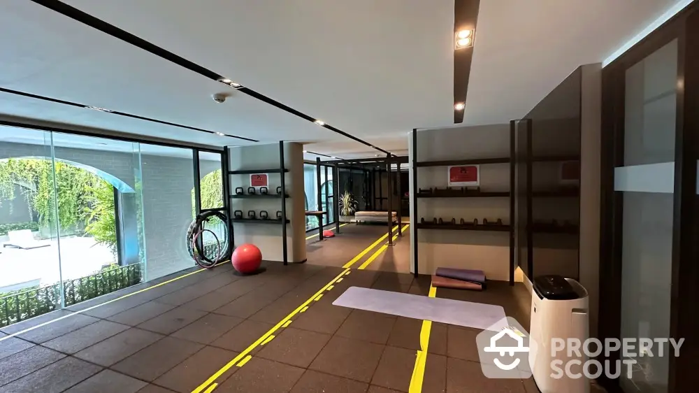 Modern gym with large windows and exercise equipment in upscale residential building.