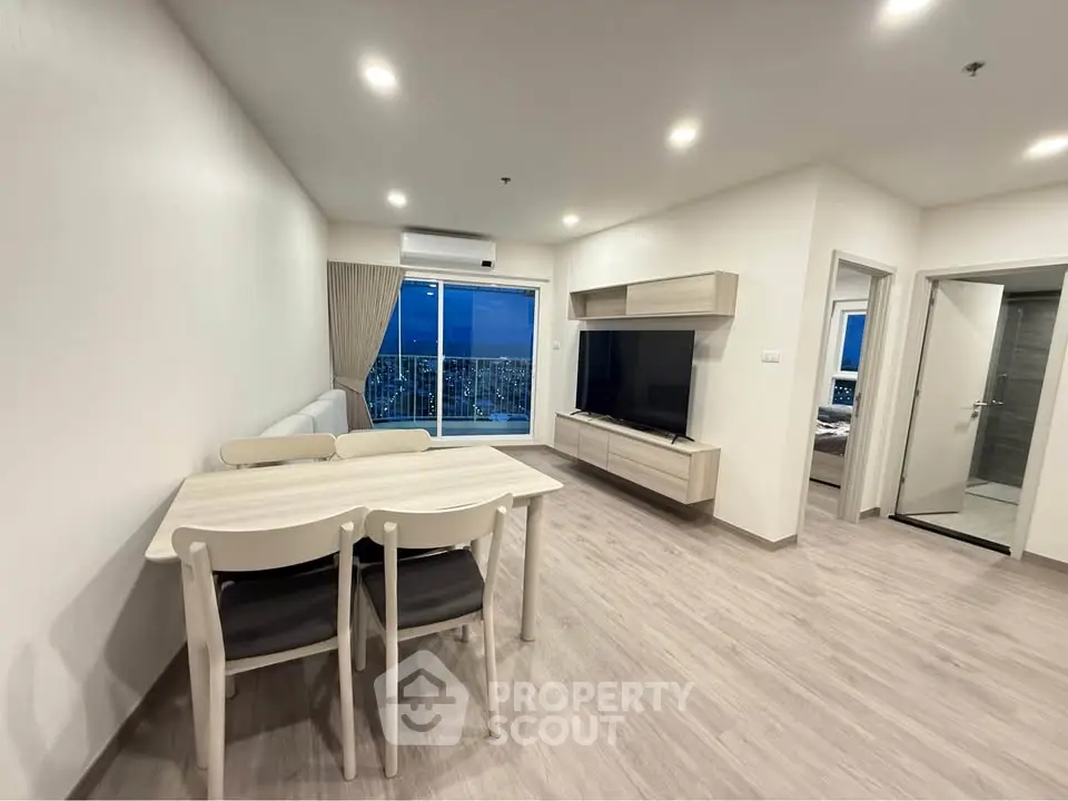 Modern living room with dining area and city view balcony in a stylish apartment.