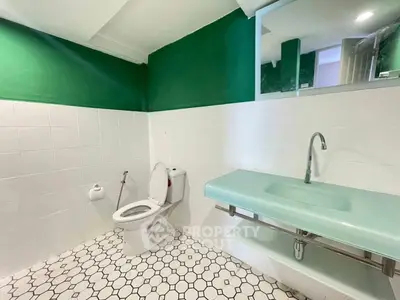 Modern bathroom with green accent wall and sleek glass sink