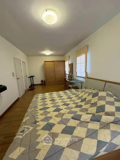 Spacious bedroom with wooden flooring and cozy decor