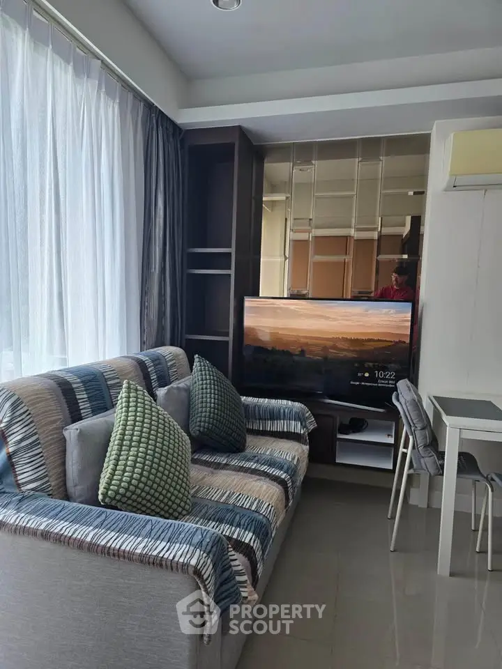 Modern living room with stylish sofa, large TV, and elegant decor in a bright apartment.