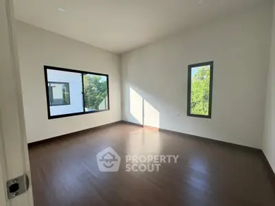 Spacious empty room with large windows and wooden flooring, perfect for customization.