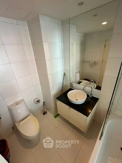 Modern bathroom with sleek white tiles and stylish fixtures, featuring a contemporary sink and toilet.