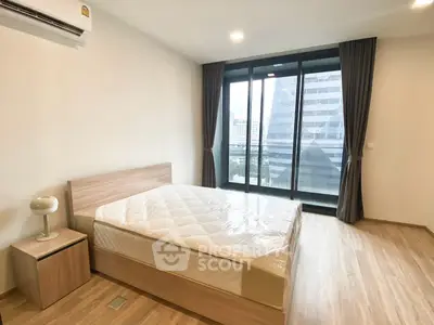 Modern bedroom with large window and city view, featuring a comfortable bed and wooden flooring.