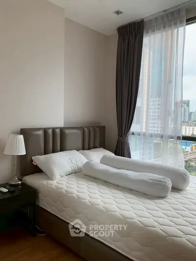 Modern bedroom with city view, featuring a stylish bed and floor-to-ceiling window.