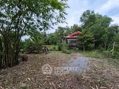 Charming rural property with lush greenery and cozy red-roofed house, perfect for nature lovers.