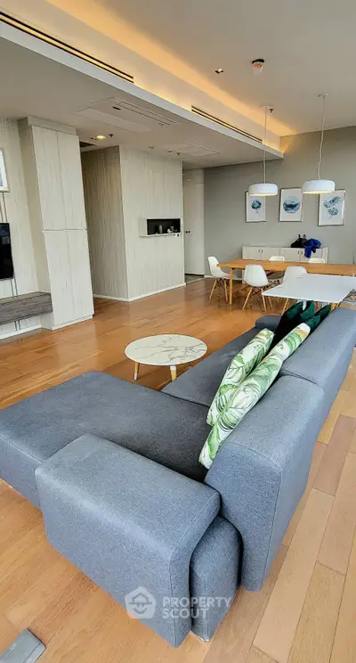 Modern living room with stylish furniture and dining area, featuring wooden flooring and elegant decor.
