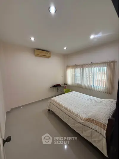 Spacious bedroom with modern lighting and large window for natural light.