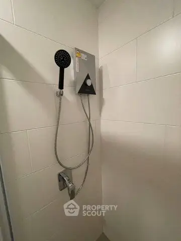 Modern bathroom shower with sleek white tiles and handheld showerhead.