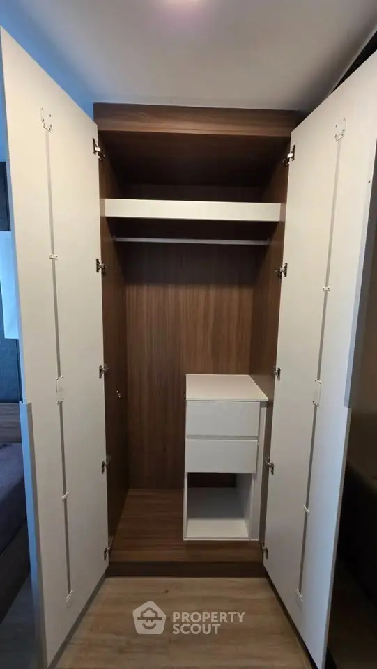 Spacious modern wardrobe with open doors and built-in drawers in a stylish bedroom.