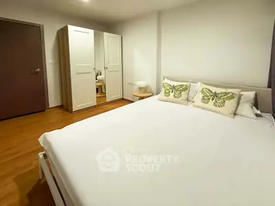 Cozy bedroom with wooden flooring and stylish wardrobe, perfect for relaxation.