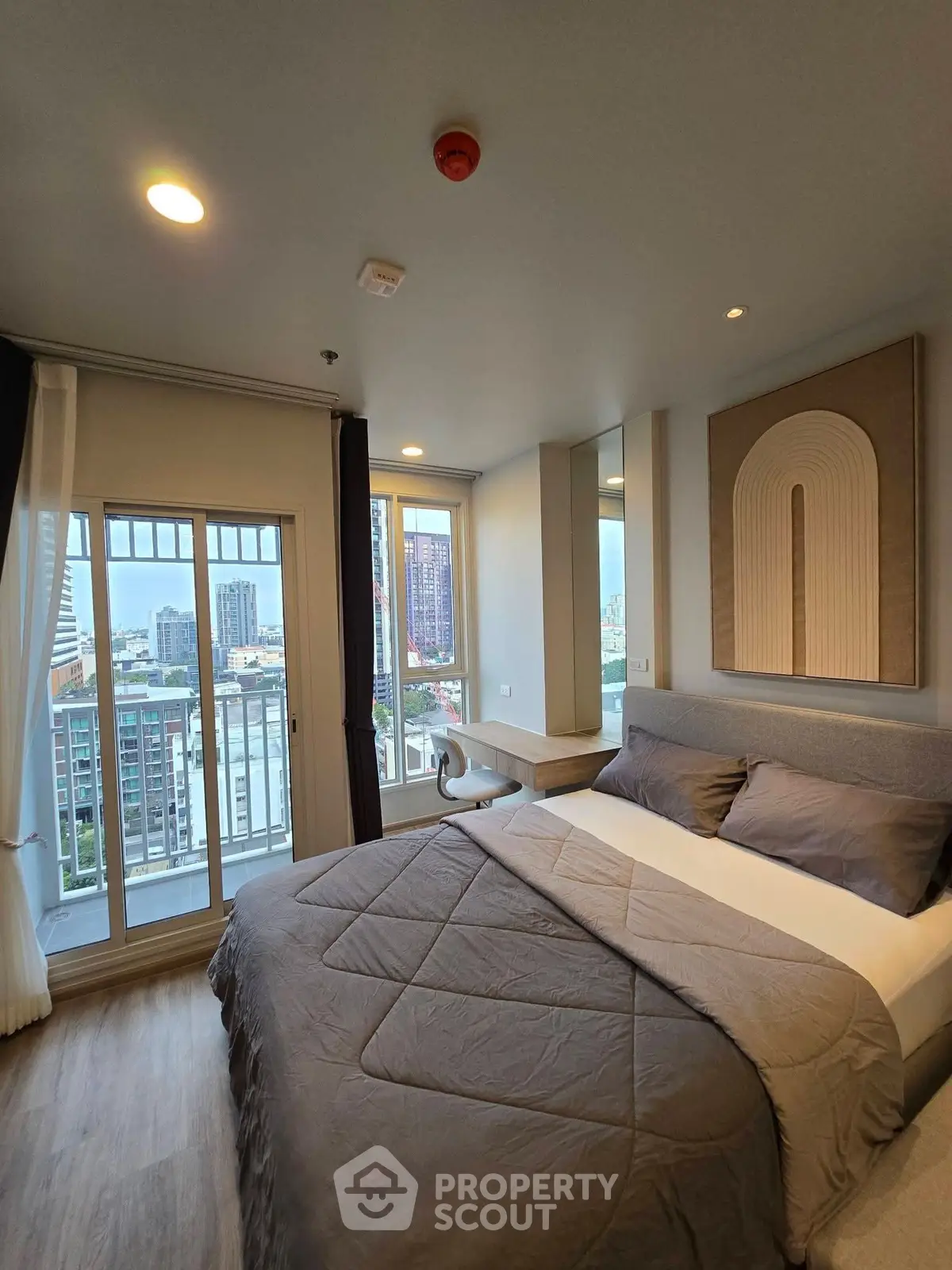Modern bedroom with city view and stylish decor in high-rise apartment.