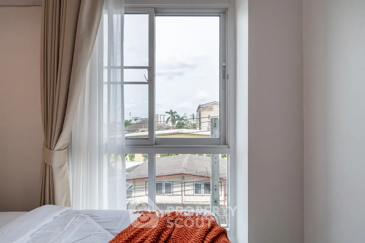 Bright bedroom with city view through large window and cozy decor