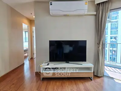 Modern living room with large TV and balcony view in high-rise apartment.