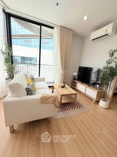 Modern living room with large windows, stylish furniture, and wooden flooring in a high-rise apartment.