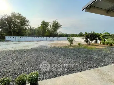 Spacious outdoor area with gravel and greenery, ideal for landscaping or development.