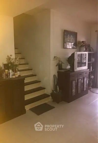 Cozy living room with staircase and vintage TV cabinet, perfect for family gatherings.