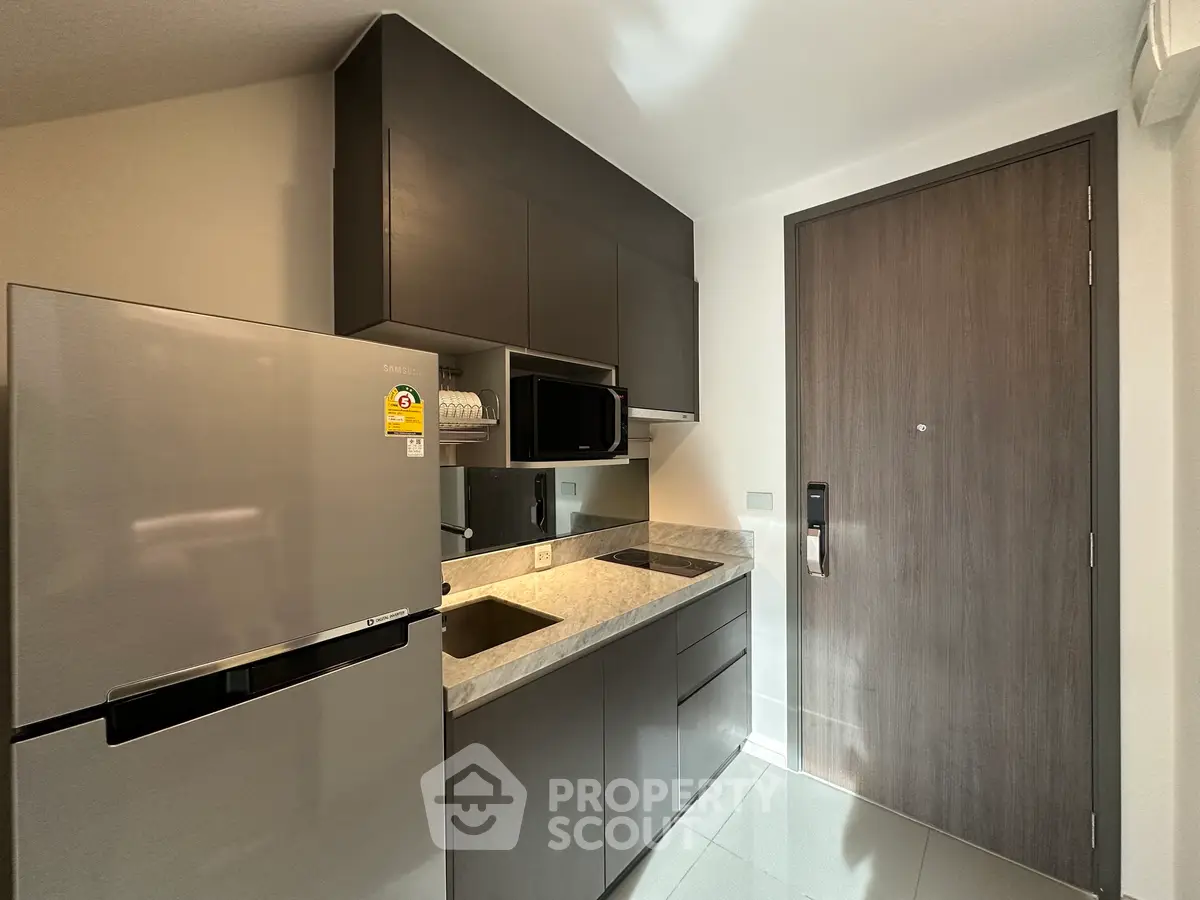 Modern compact kitchen with sleek cabinetry and stainless steel appliances in a stylish apartment.
