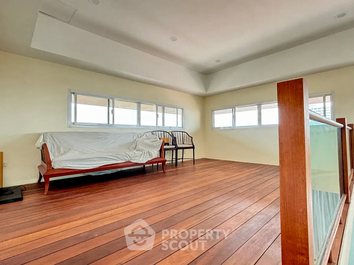 Spacious room with wooden flooring and large windows, perfect for a cozy living area.