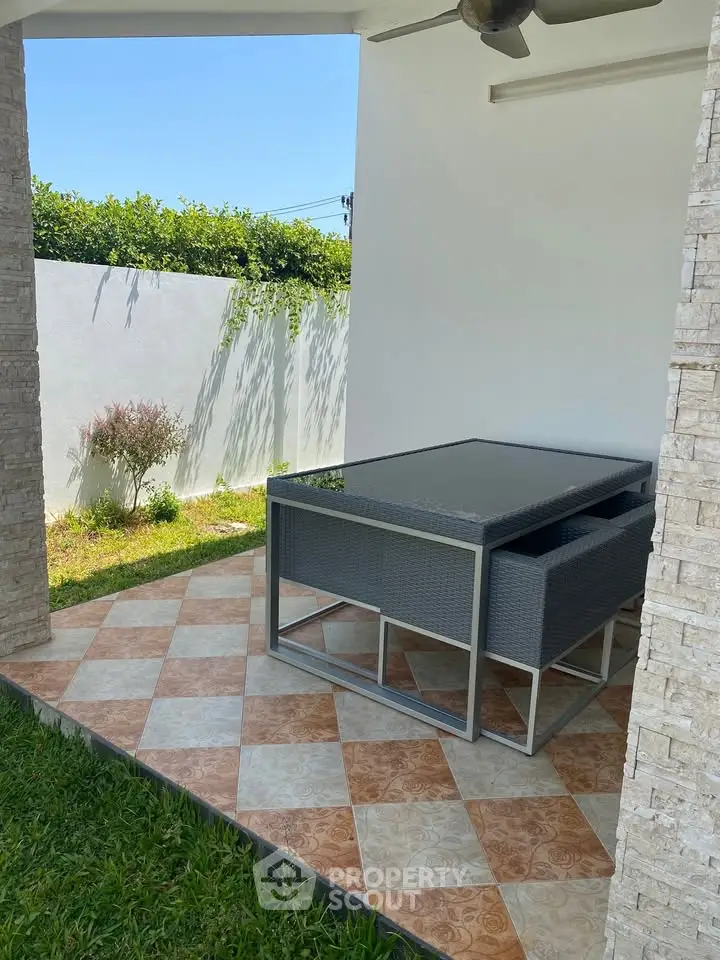 Charming outdoor patio with modern furniture and lush garden view, perfect for relaxation and entertaining.