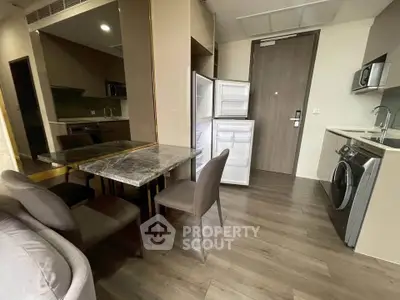Modern apartment kitchen with open fridge, washing machine, and dining area.