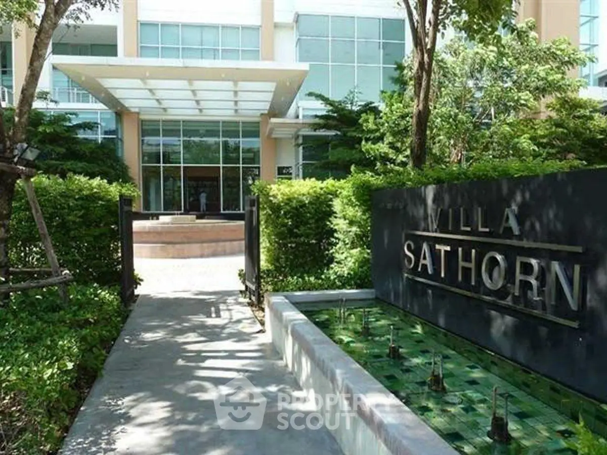 Elegant entrance of Villa Sathorn with lush greenery and modern architecture.