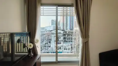 Modern living room with large window offering stunning city view, elegant curtains, and stylish decor.