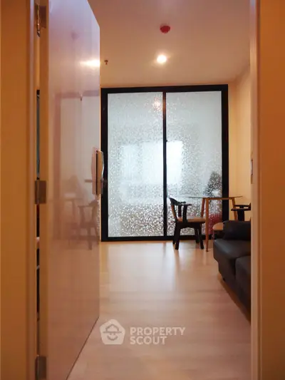 Modern apartment entrance with frosted glass sliding doors and cozy seating area.