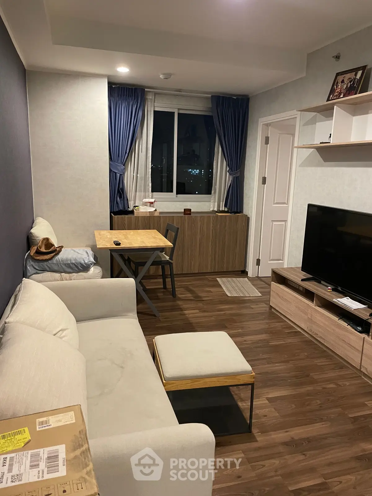 Cozy living room with modern decor, featuring a comfortable sofa, dining table, and large TV for entertainment.