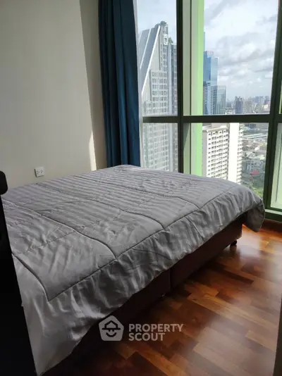 Modern bedroom with city view and large windows in high-rise apartment