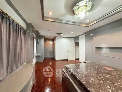 Spacious bedroom with elegant chandelier and polished wooden floors