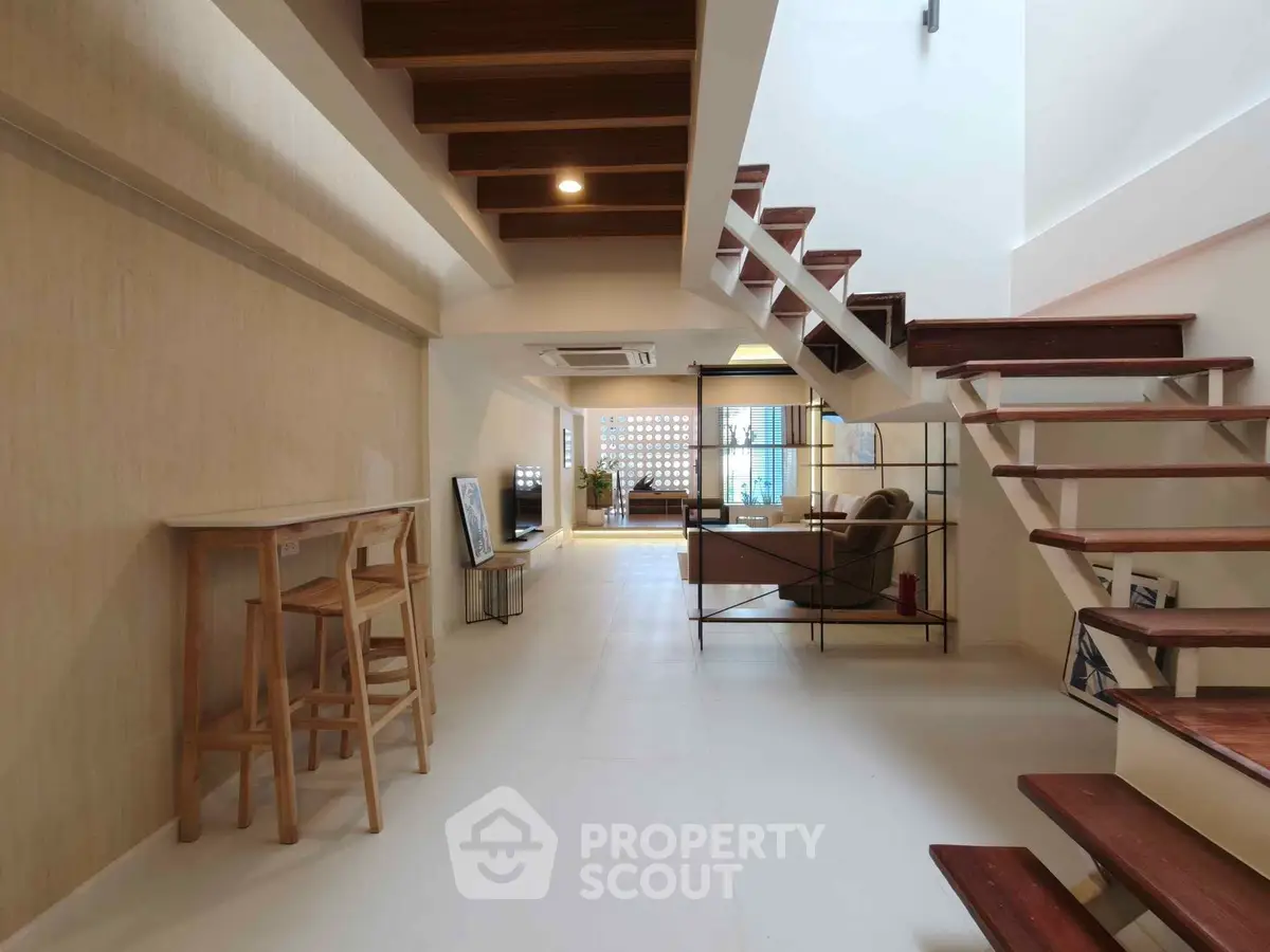 Modern open-plan living area with stylish staircase and wooden accents