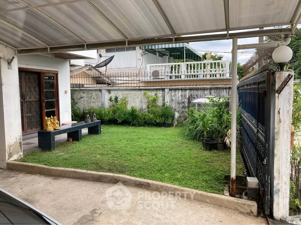 Charming residential garden with lush greenery and secure gated entrance, perfect for relaxation and privacy.