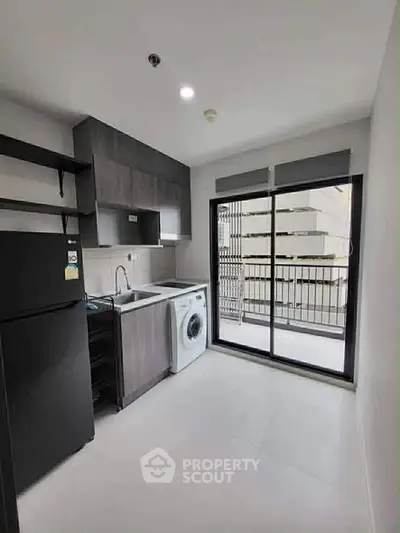 Modern kitchen with washing machine and balcony view in sleek apartment.