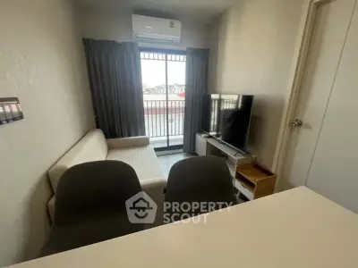 Cozy living room with sofa, TV, and balcony access in modern apartment.