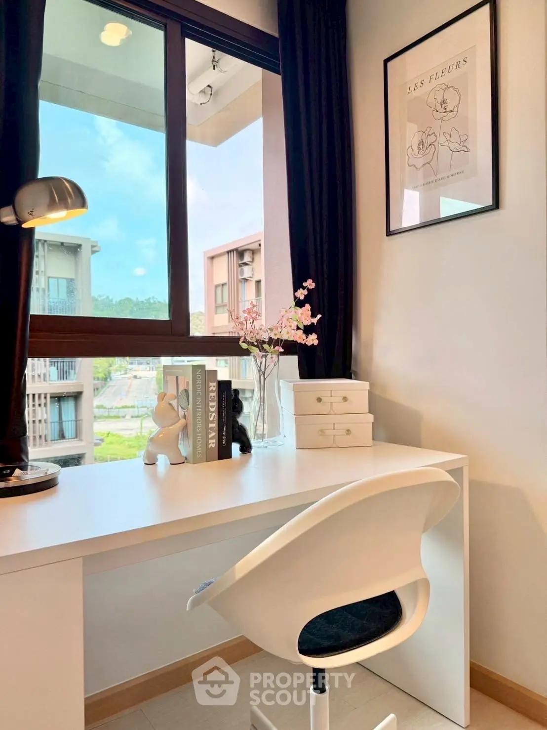 Modern study room with sleek white desk and chair, large window view, and stylish decor.