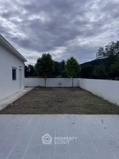 Spacious backyard with tiled patio and lush greenery, perfect for outdoor activities and relaxation.